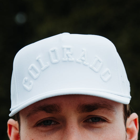 White Colorado performance hat with tonal white raised embroidery, white rope detail, and model front close-up.