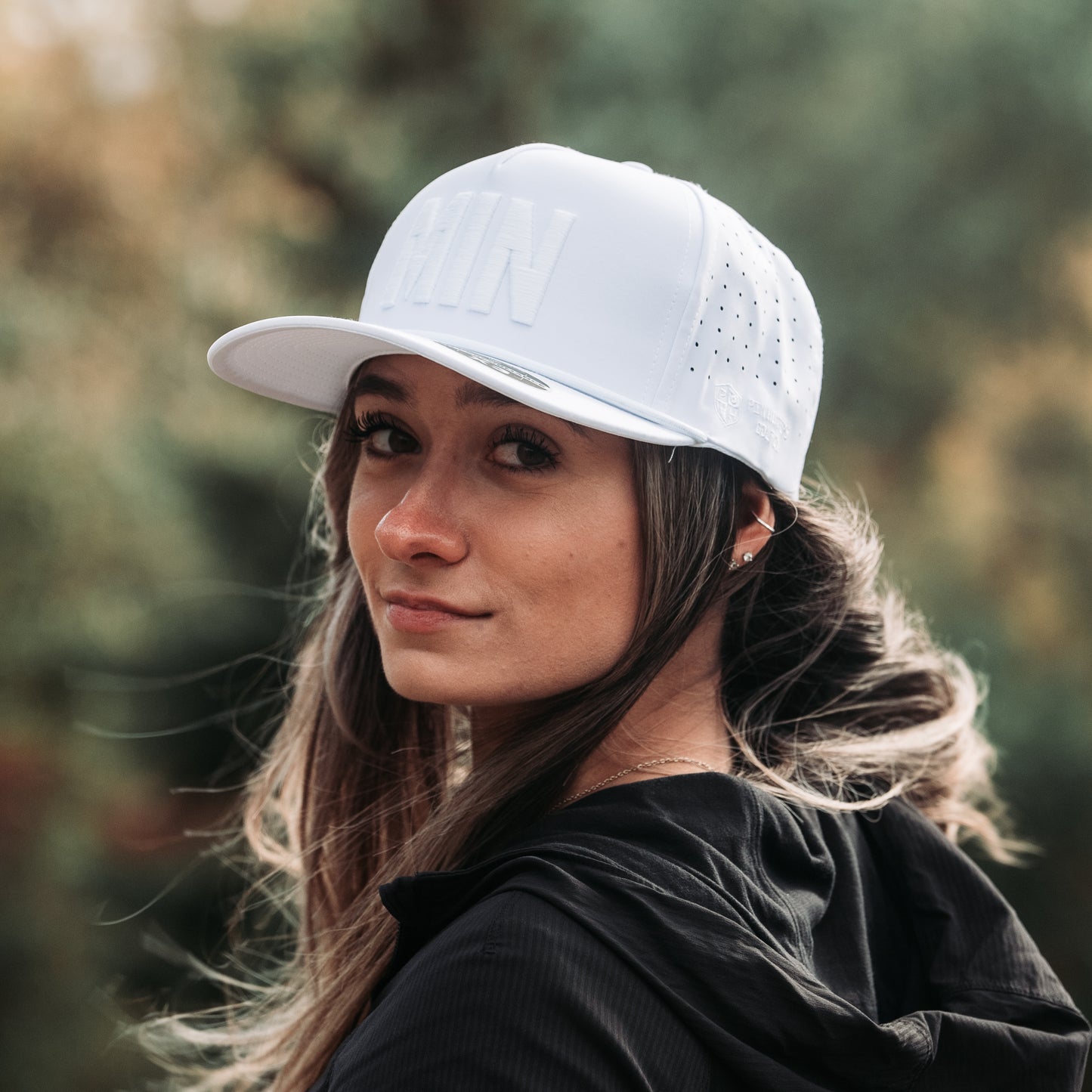 White tonal MIN performance golf hat on model with raised white embroidery, matching white rope detail, and perforated side panels.