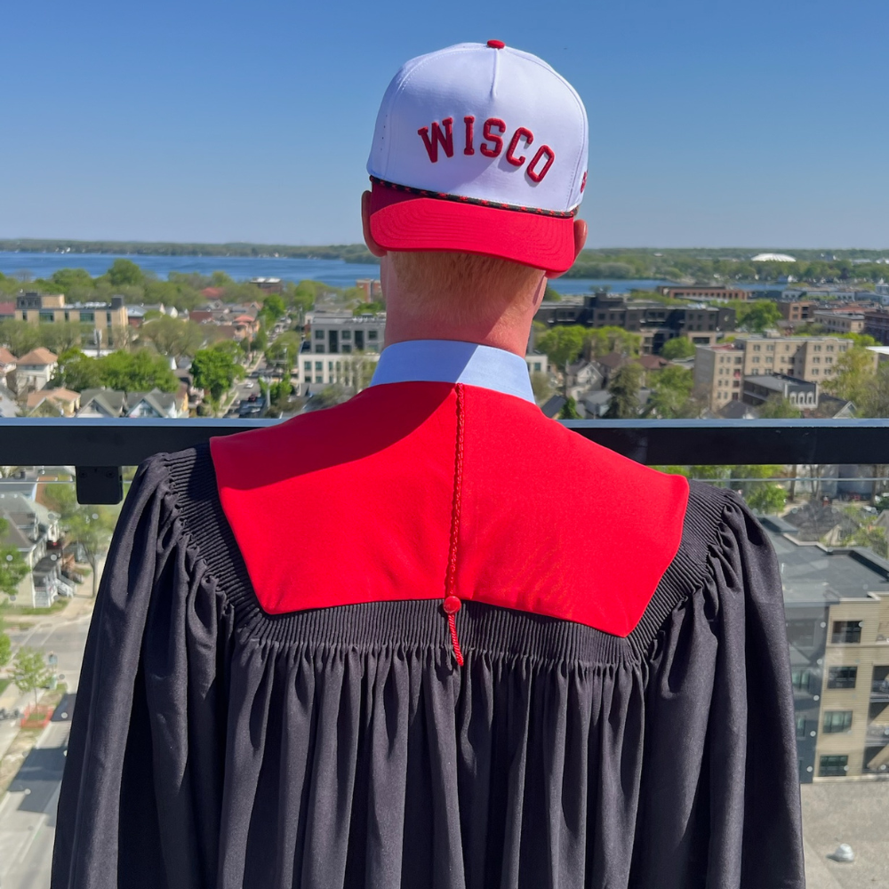 Matthew Paul in a Wisco hat and graduation gown overlooking Madison