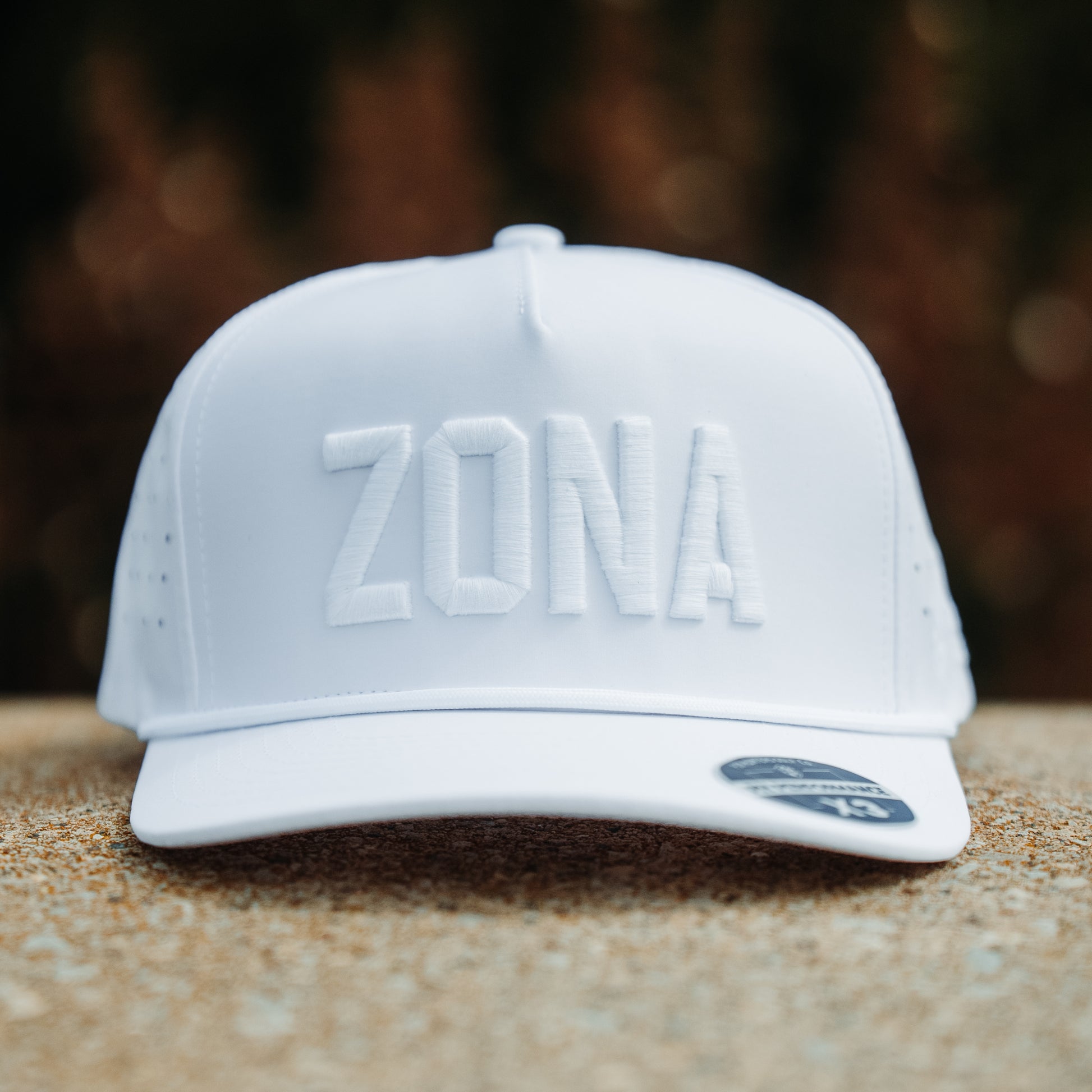 Arizona Cardinals inspired white Zona tonal performance hat with white raised embroidery, matching rope detail, and outdoor stone display.
