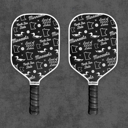 Black and white Minnesota pickleball paddle pair with loon, state outline, North Star State, and Land of 10,000 Lakes pattern.