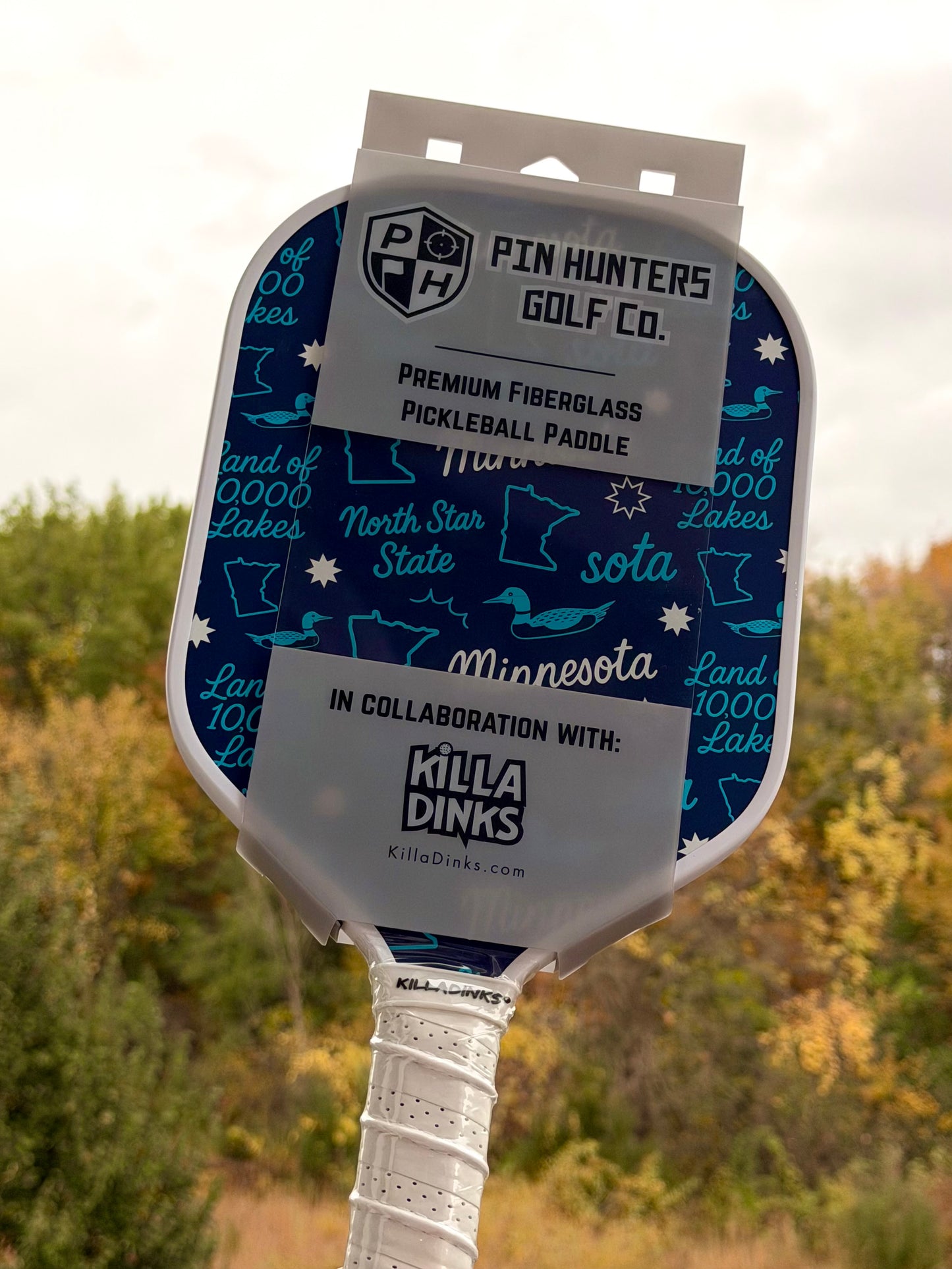 Blue Minnesota pickleball paddle with teal Land of 10,000 Lakes, loon, Minnesota, and North Star State graphics in Killa Dinks packaging.