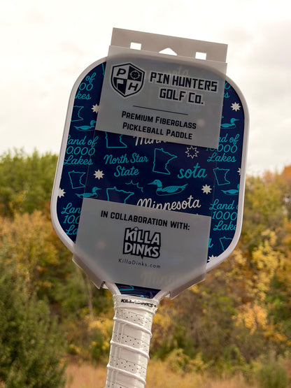 Blue Minnesota pickleball paddle with teal Land of 10,000 Lakes, loon, Minnesota, and North Star State graphics in Killa Dinks packaging.