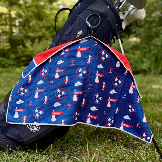 Blue Tennessee inspired golf towel hanging from a golf bag with Tennessee state, TriStar, music, cowboy hat, and golf graphics.