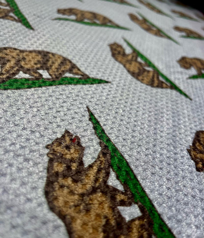 Close up of a California Republic golf towel showing the bear design, green grass detail, and microfiber waffle towel texture.