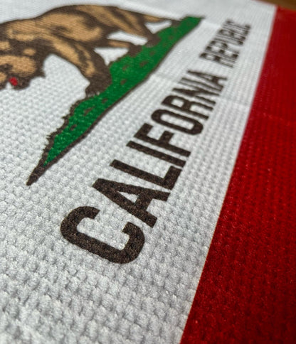 Close up of a California Republic golf towel showing printed bear, star, red stripe, and microfiber towel texture.