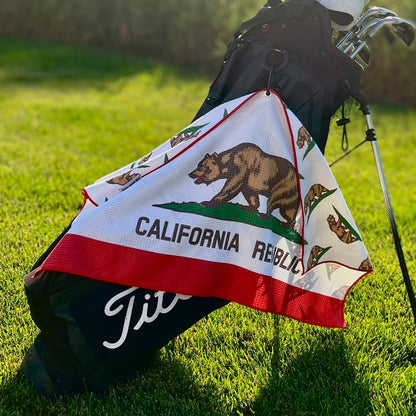 California Republic golf towel hanging from a golf bag with bear flag inspired front design, red trim, and white microfiber fabric.