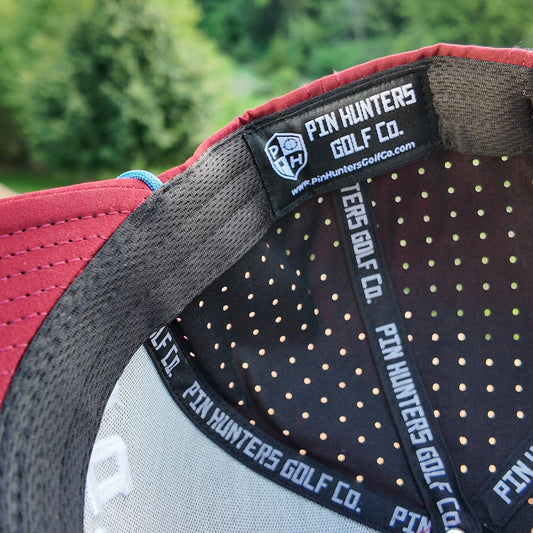 Interior detail of the Colorado Avalanche performance golf hat showing the Pin Hunters Golf Co. label, perforated lining, and branded inner taping.