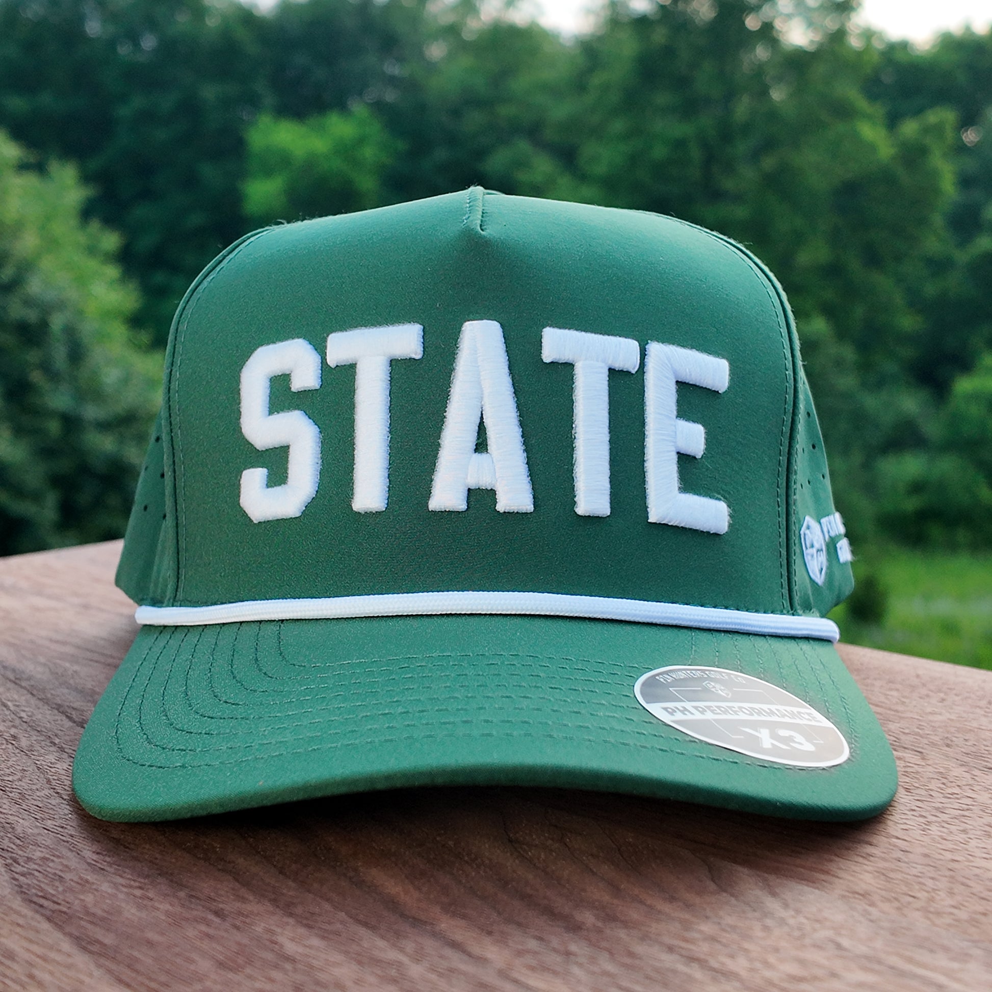 Front view of the Colorado State green performance golf hat with raised white STATE embroidery, white rope, flat brim, and PH Performance sticker.