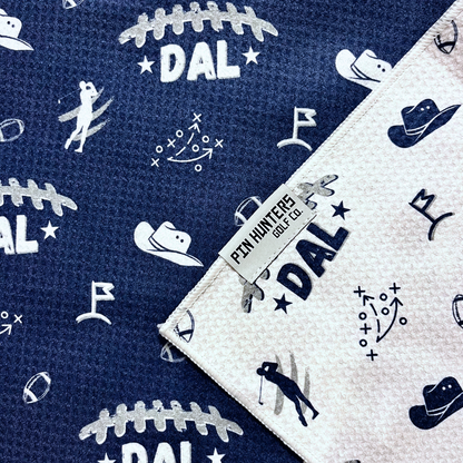 Dallas Cowboys inspired golf towel close-up showing navy and white towel patterns with football, cowboy hat, golf flag, play diagram, and Pin Hunters label.