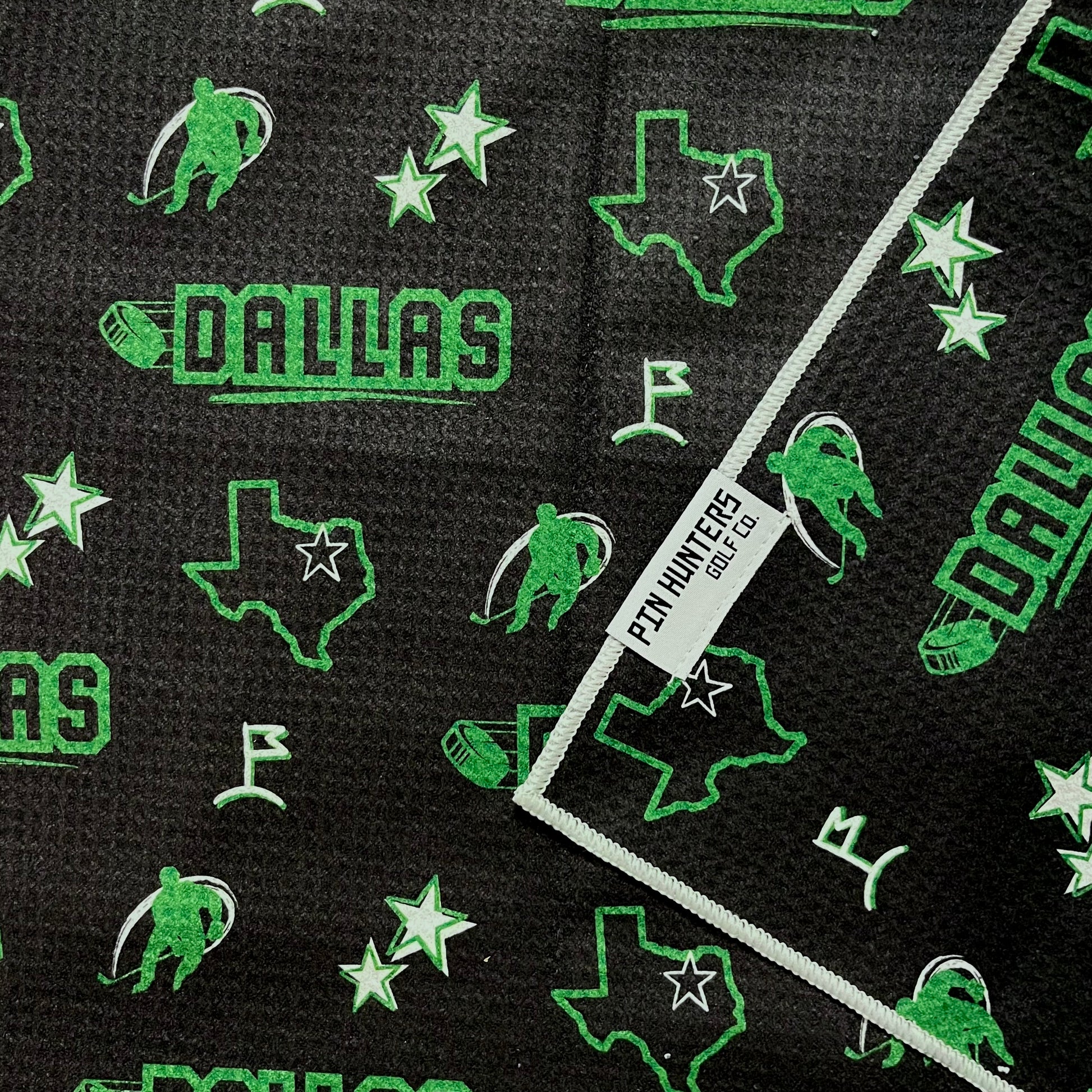 Dallas Stars hockey golf towel close-up with black waffle microfiber, green Dallas text, Texas outlines, stars, and hockey player icons.