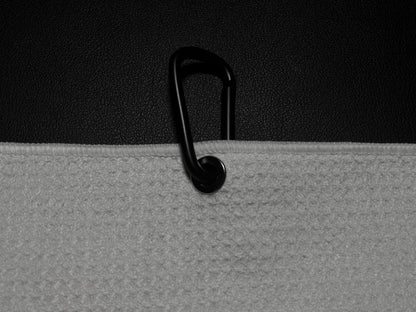 Close up product detail of a golf towel carabiner clip and towel edge against a black golf bag.