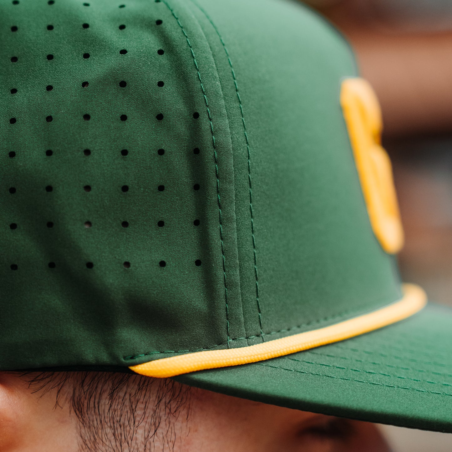Close up of Green Bay packers performance hat with gold rope, perforated side panels, and structured performance fabric.
