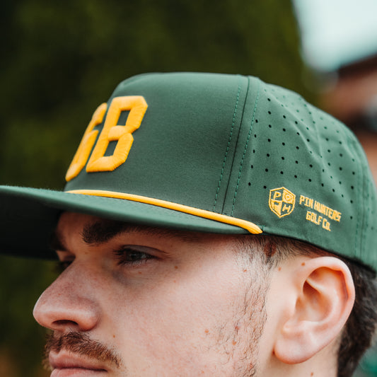 Green GB performance golf hat side detail with yellow Pin Hunters logo embroidery, yellow rope detail, perforated side panels, and raised front embroidery.