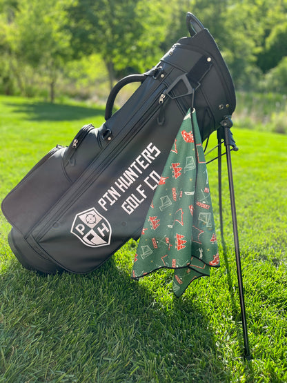 Green Minnesota Wild inspired hockey golf towel hanging from a black Pin Hunters golf bag with red and white hockey, state, and golf graphics.