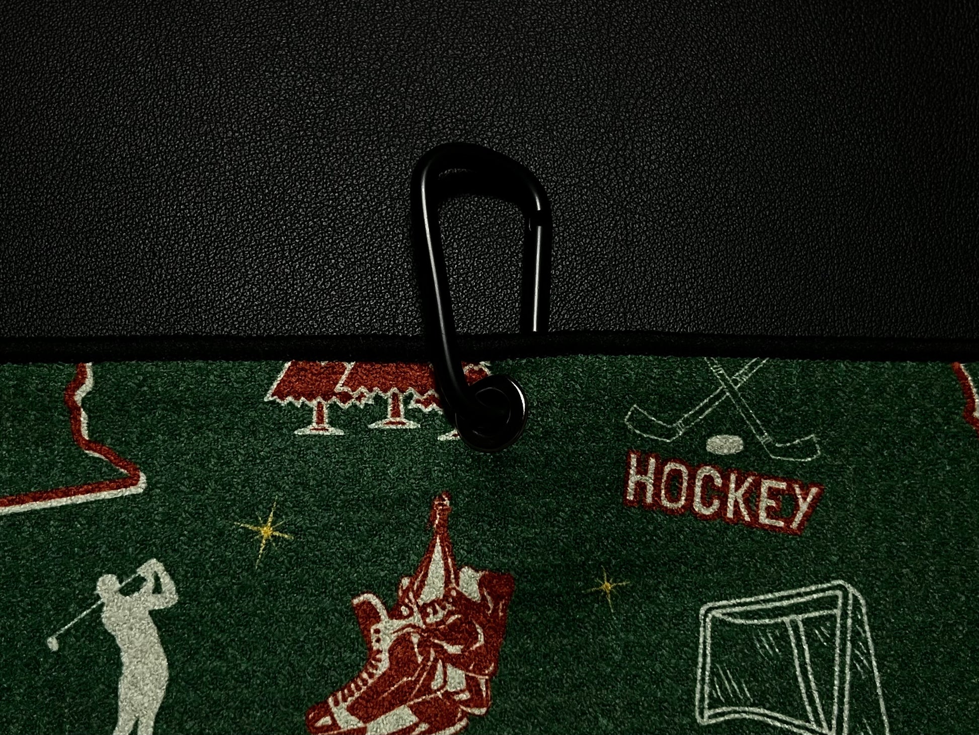 Close up of a green Minnesota Wild inspired hockey golf towel clipped to a black golf bag with hockey skates, net, sticks, MN text, and Pin Hunters label.