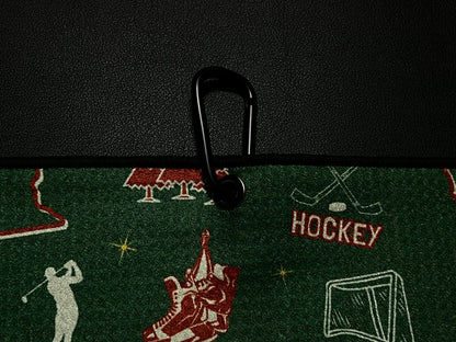 Close up of a green Minnesota Wild inspired hockey golf towel clipped to a black golf bag with hockey skates, net, sticks, MN text, and Pin Hunters label.