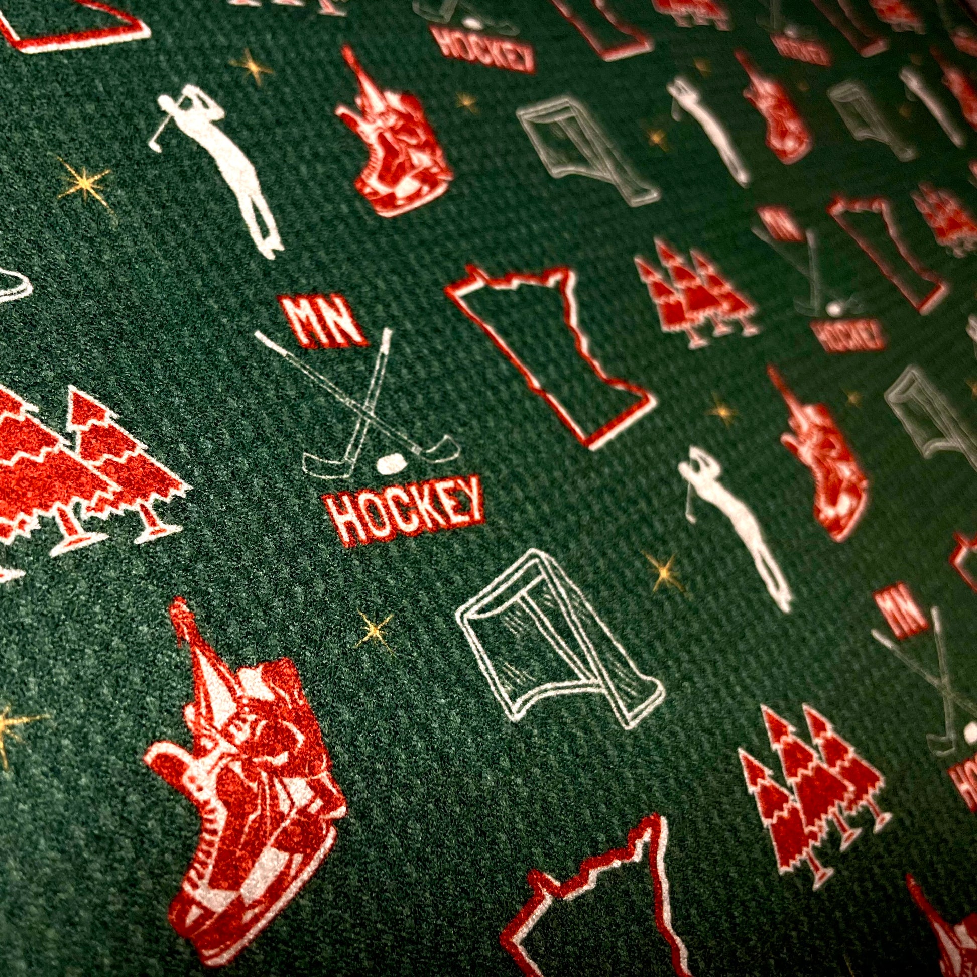 Close up of a green Minnesota Wild inspired hockey golf towel with red and white hockey, state, trees, skates, and golfer graphics.