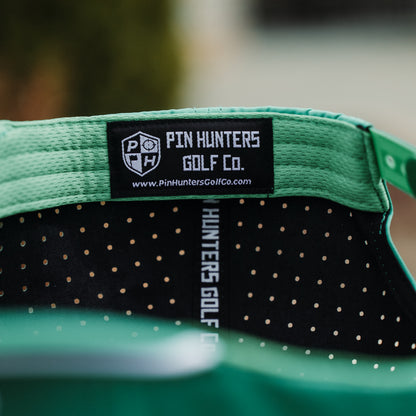 Green Pin Hunters performance golf hat interior with black woven label, branded seam tape, and perforated black inner fabric.