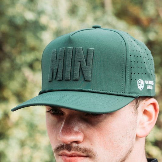 Green tonal MIN performance golf hat with raised matching MIN embroidery, side logo, perforated panels, and flat brim.