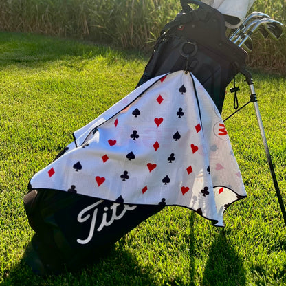 Las Vegas golf towel hanging from a black golf bag, showing the playing card suit back pattern with hearts, diamonds, clubs, and spades.