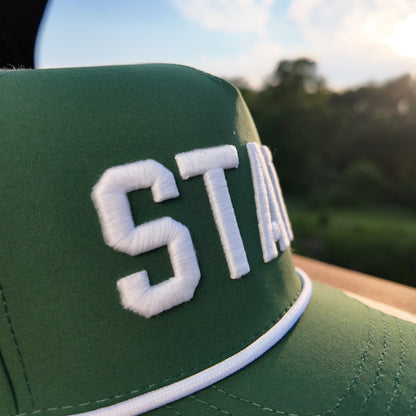 Close up of the Michigan State green performance golf hat with raised white STATE embroidery, white rope, green crown, and stitched front panel.