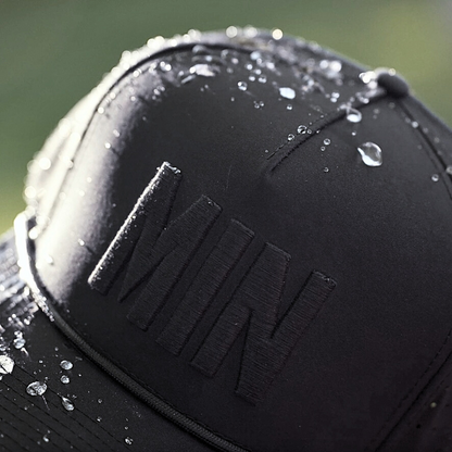Blackout Minnesota performance hat close-up with tonal black MIN raised embroidery, water droplets, black rope detail, and water-resistant fabric.