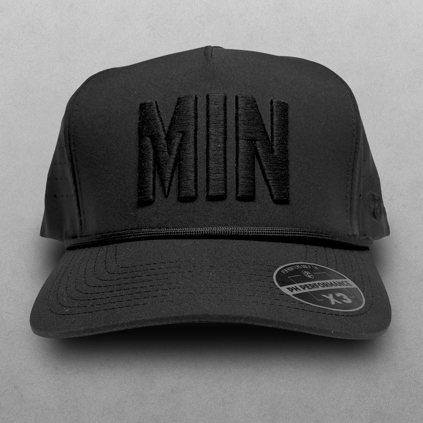 Blackout Minnesota performance hat with tonal black MIN raised embroidery, black rope detail, perforated side panels, and PH Performance X3 sticker.