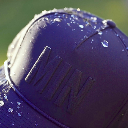 Purple tonal Minnesota performance hat close-up with dark MIN raised embroidery, water droplets, rope detail, and water-resistant fabric.