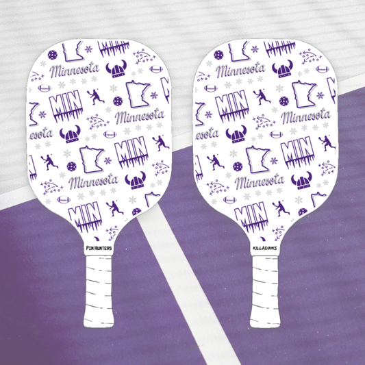 Minnesota Vikings pickleball paddle pair on court with purple MIN pattern, football icons, helmet graphics, and white handles.