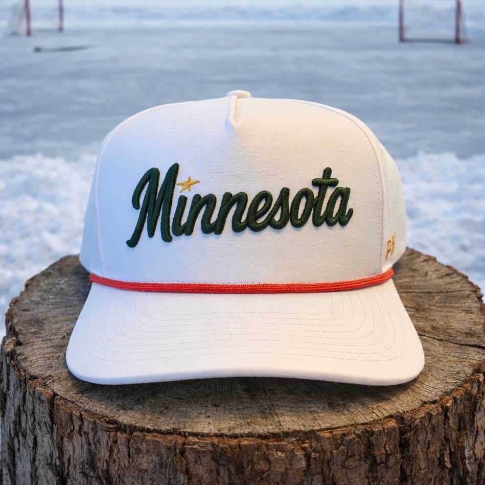 Minnesota Wild inspired white performance hat with green script embroidery, gold star accent, red rope detail, and snowy outdoor stump background.