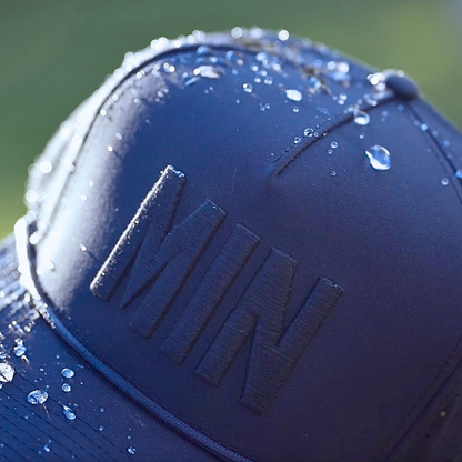 Navy tonal MIN performance golf hat close-up with matching raised embroidery, water droplets, and navy performance fabric.
