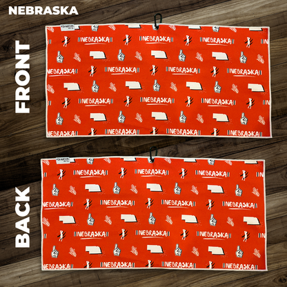 Nebraska golf towel layout with orange background, state outline, corn, foam finger, golfer, and repeating Nebraska text icons.