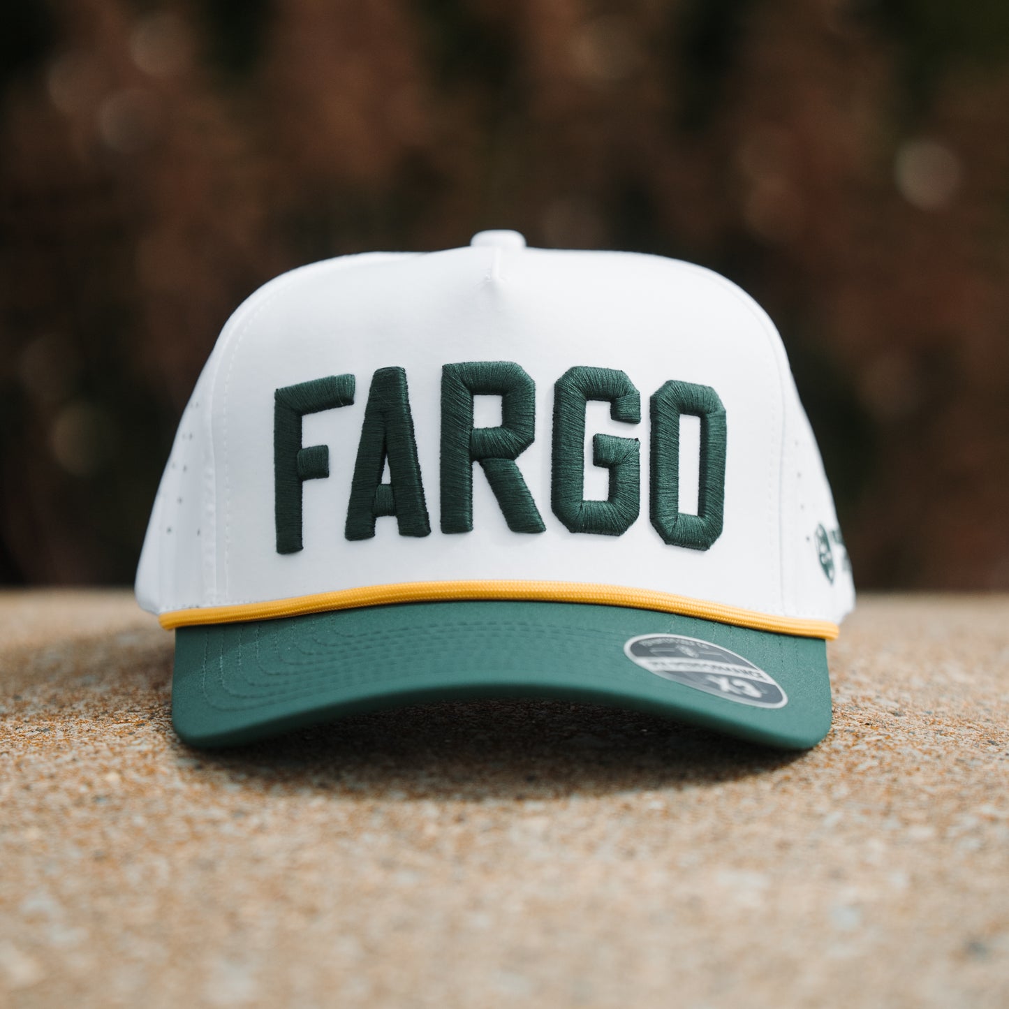 North Dakota State Bison Fargo performance hat front view with white crown, green raised embroidery, green brim, yellow rope, and PH Performance X3 sticker.