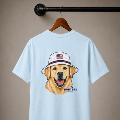 Baby blue Pin Hunters Colby Tee hanging from an industrial pipe with golden retriever golf design printed on the back.
