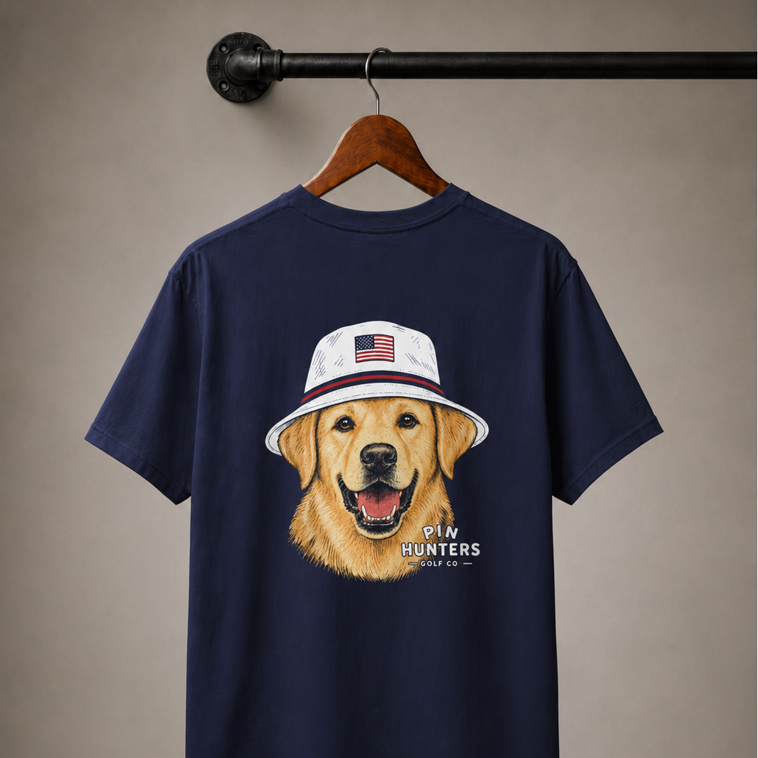 True Navy Pin Hunters Colby Tee displayed on a wooden hanger with golden retriever patriotic golf hat graphic on the back.