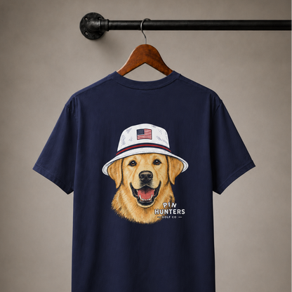 True Navy Pin Hunters Colby Tee displayed on a wooden hanger with golden retriever patriotic golf hat graphic on the back.