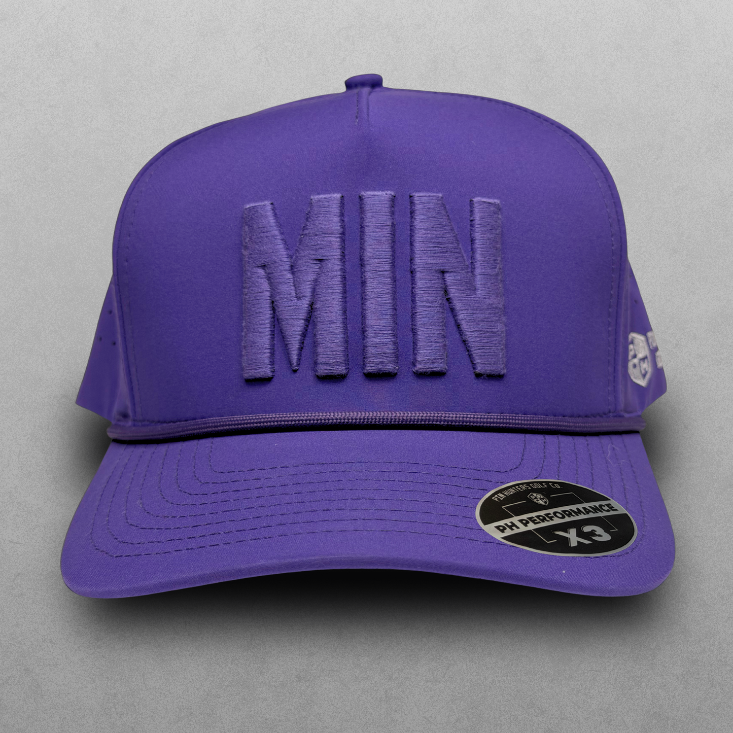 Front view of the purple MIN Performance Hat by Pin Hunters Golf Co. with tonal raised MIN embroidery, matching rope detail, and structured 5-panel design.
