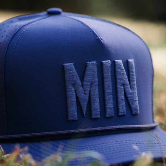 Side profile of the purple MIN Performance Hat with structured 5-panel fit, tonal raised embroidery, rope detail, and perforated side panels.