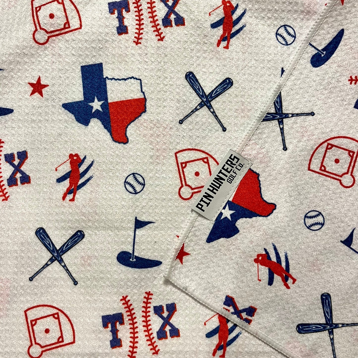 Close up of Texas Rangers golf towel with red, white, and blue Texas, baseball, crossed bats, golfer, and golf flag graphics.