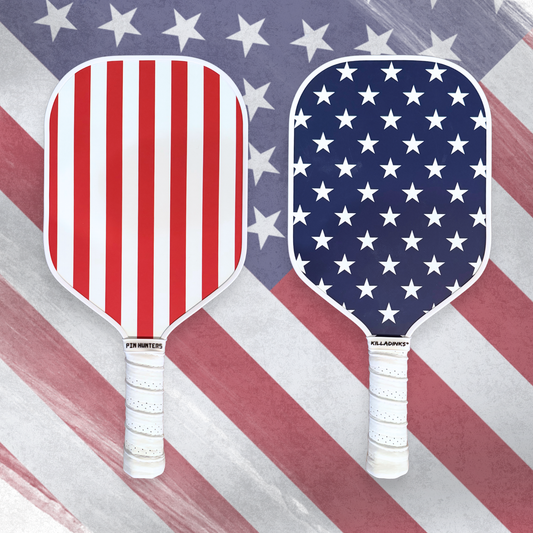 USA patriotic pickleball paddles with red and white stripe front, navy star pattern back, white handles, and American flag background.