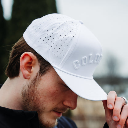 White Colorado tonal performance golf hat on model with white raised embroidery, matching rope detail, and perforated side panels.