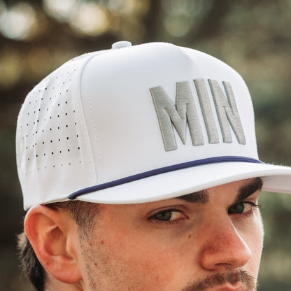 White MIN performance golf hat with gray raised embroidery, purple rope detail, perforated side panels, and model close-up.