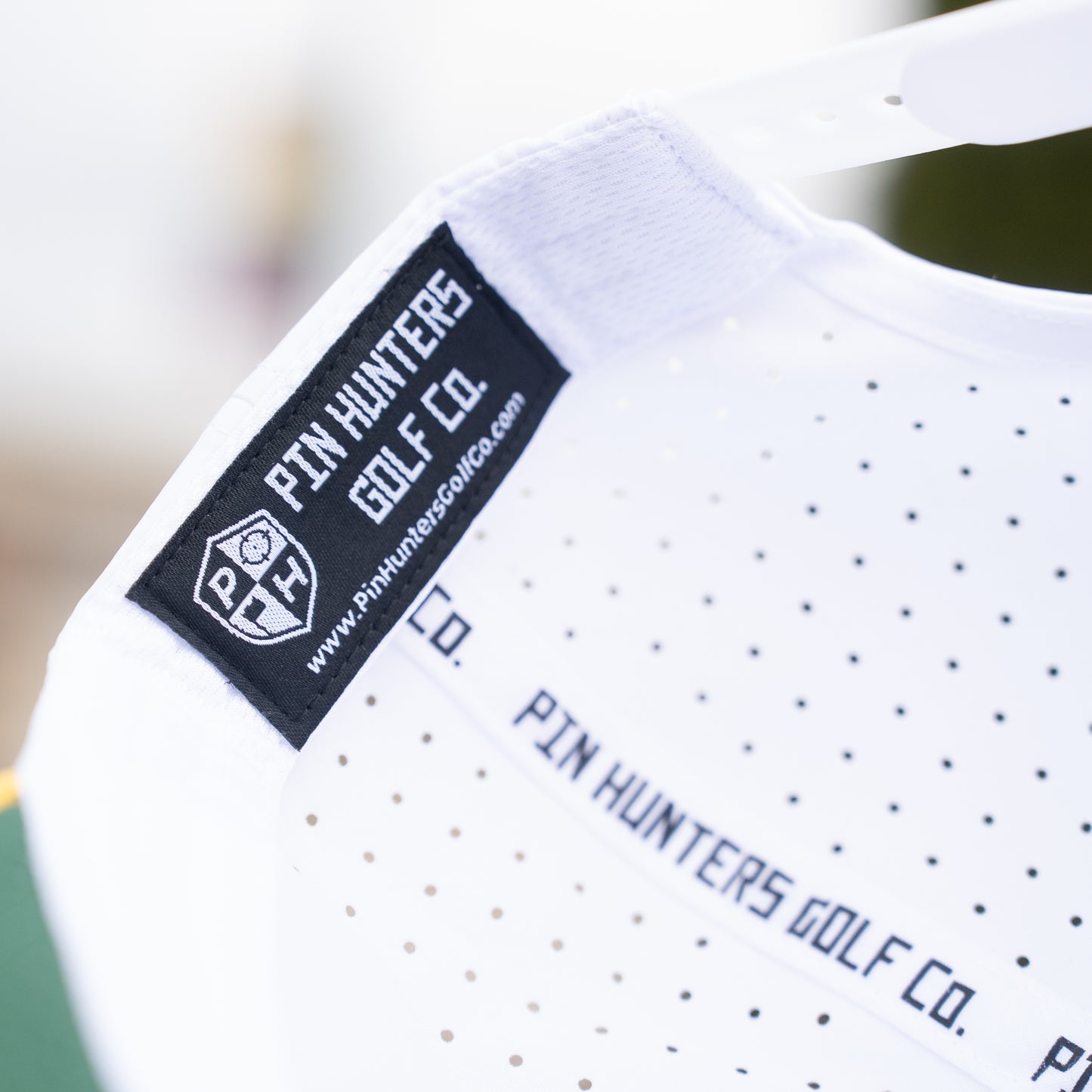 White Pin Hunters performance golf hat interior with black woven label, branded seam tape, and perforated performance fabric.