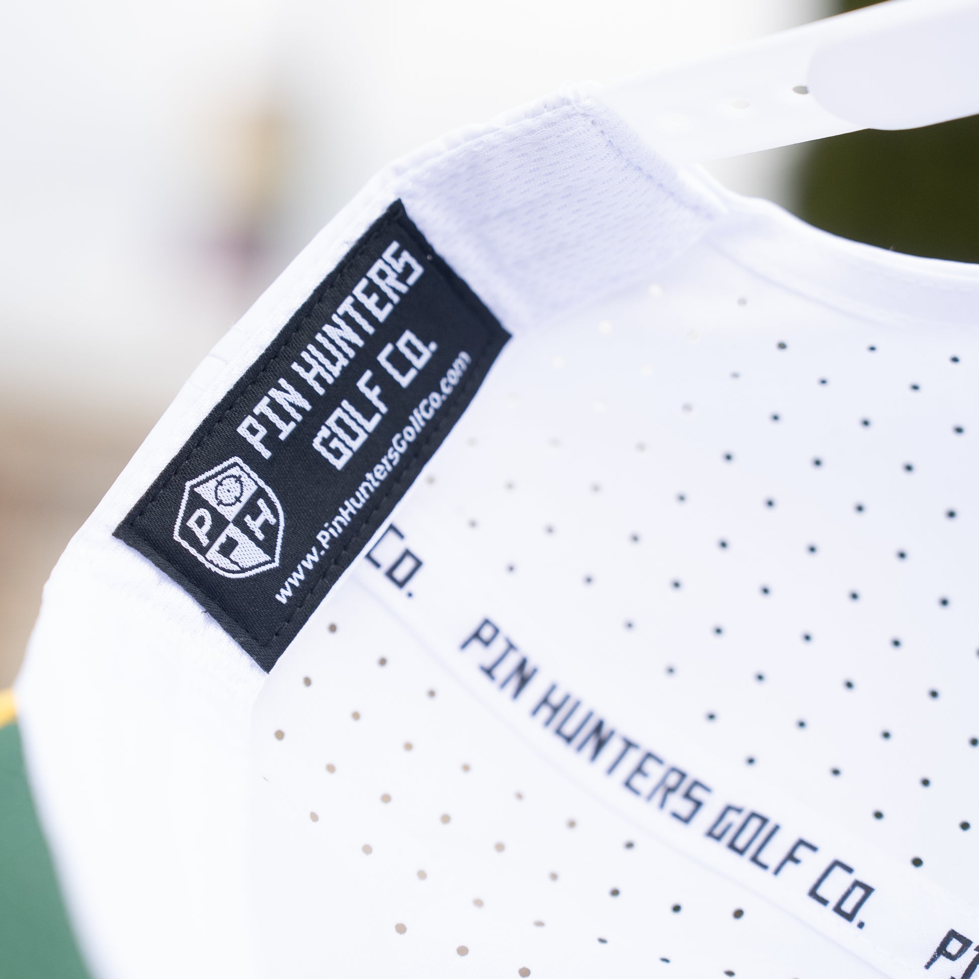 White Pin Hunters performance golf hat interior with black woven label, branded seam tape, and perforated performance fabric.