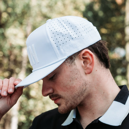 White tonal MIN performance golf hat with raised white embroidery, matching rope detail, perforated side panels, and side logo.