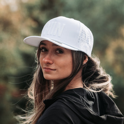 White tonal MIN performance golf hat on model with raised white embroidery, matching white rope detail, and perforated side panels.