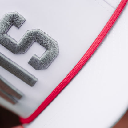 White WIS performance golf hat close-up with gray raised embroidery, red rope detail, and clean white performance fabric.
