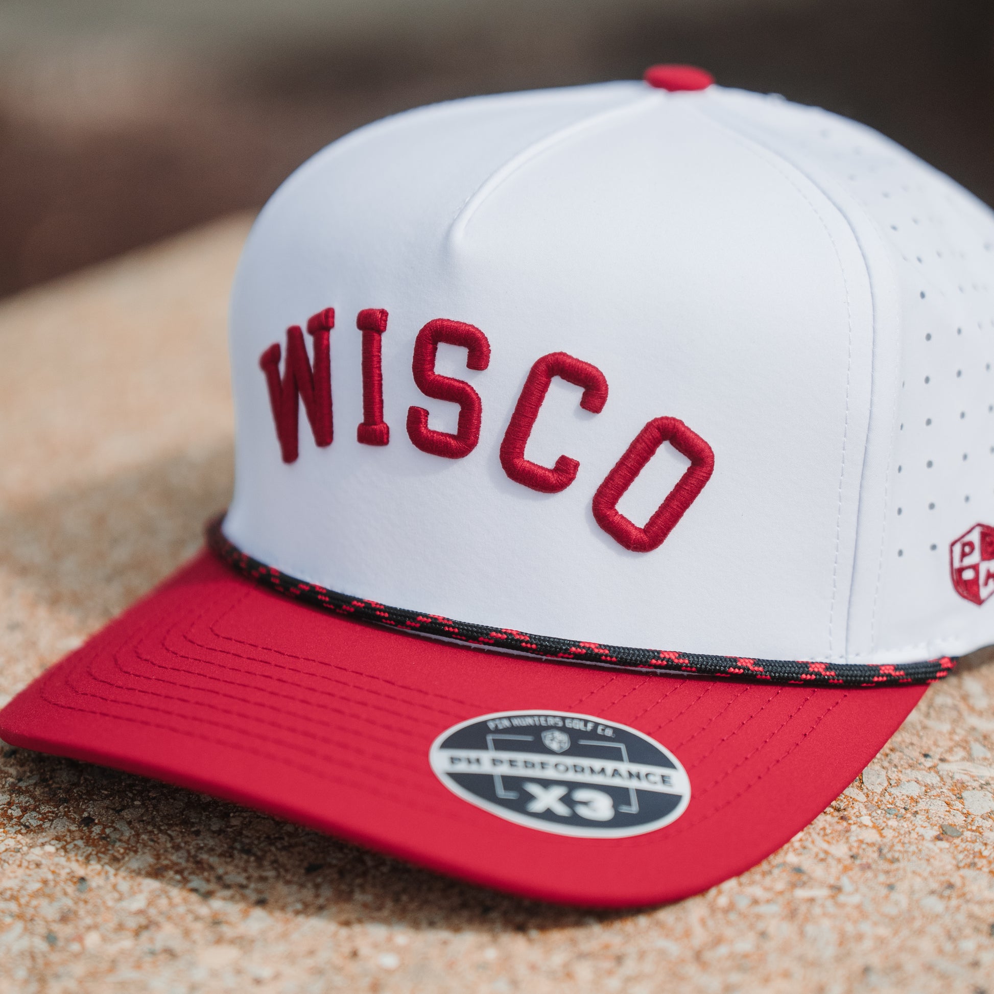 White Wisco performance golf hat with red raised embroidery, red brim, black and red rope detail, and PH Performance X3 sticker.
