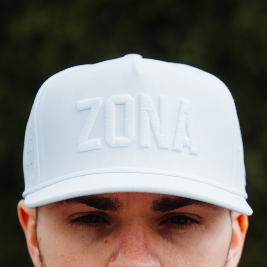 White Zona tonal performance golf hat with white raised embroidery, matching rope detail, perforated side panels, and model front view.